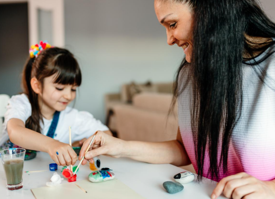 Young girl with her female art teacher, creating kindness rocks using paint - great art empowerment projects.