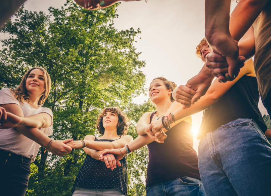 Group of diverse youth leaders forming a circle and showing unity by holding each others' hands.