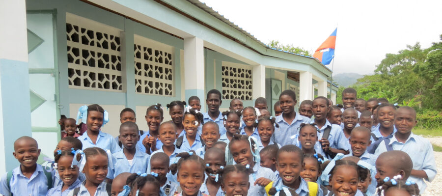 a group of students in Haiti standing in front of their school