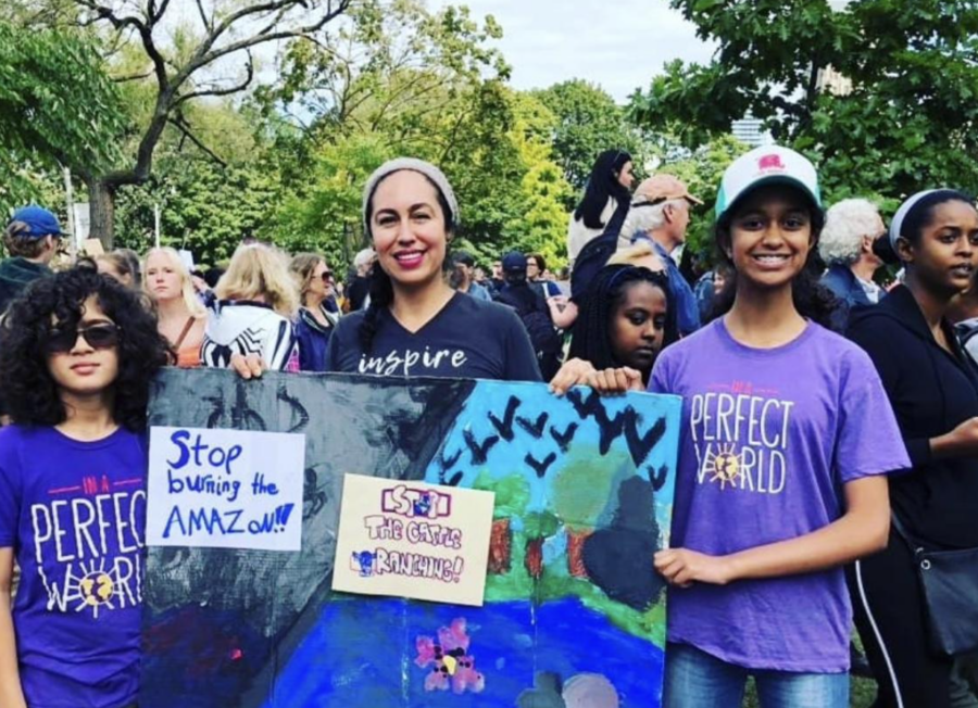 Two multi-ethnic teens holding a sign at a protest with their female teacher - empowering youth leadership in the community.