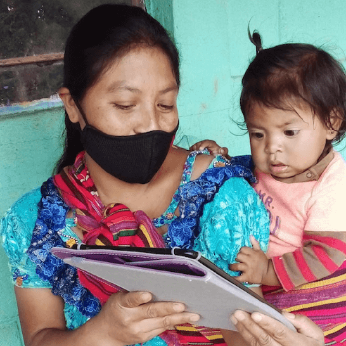 a young girl and a baby look at a tablet they received to help with their education