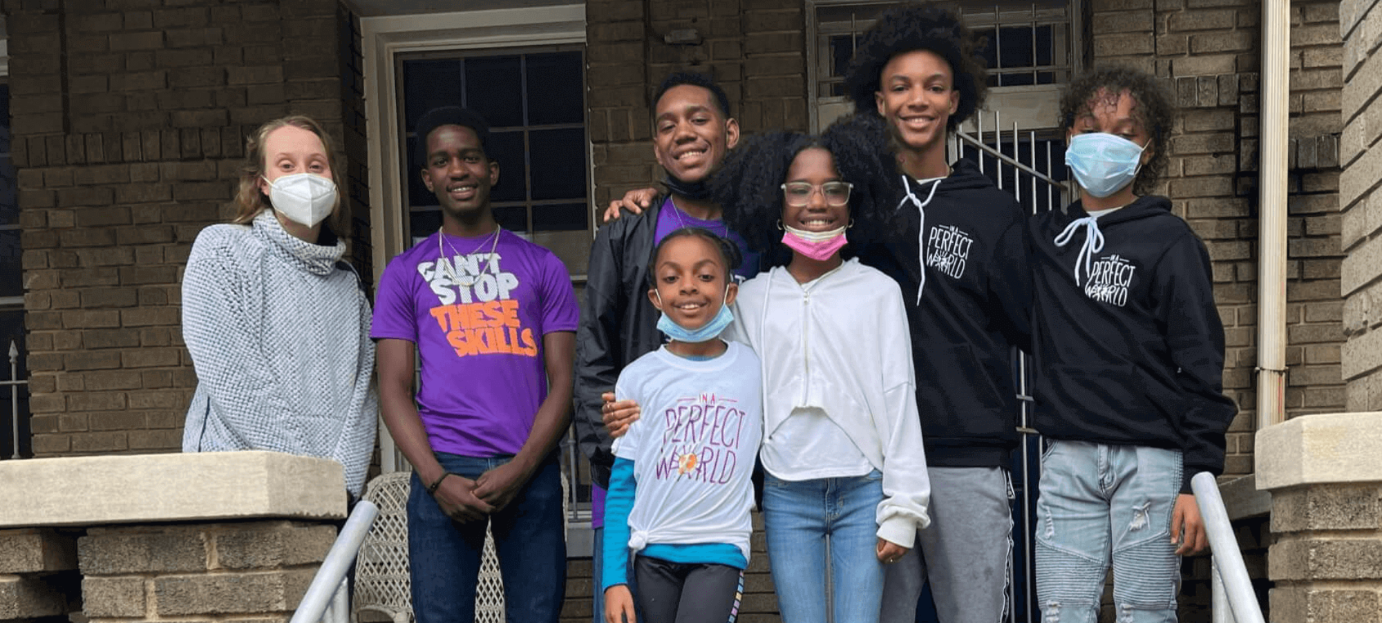 youth activists stand on top of a step in front of their house while raising money for their project