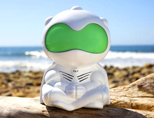 a plastic robot sits in a meditation posture with folded legs and hands. He is white and hads very large green goggles on