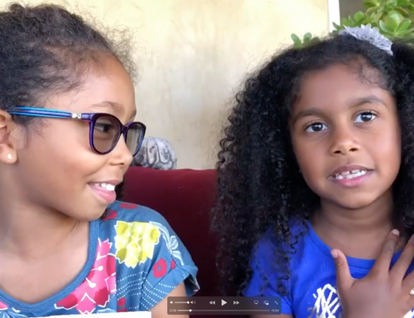 two young girls in blue tops talk about the breathing exerv=cises they do during the Covid Pandemic to calm themselves and not feel scared