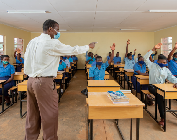 a teacher engages a group of students in a new classroom in Mbongozi