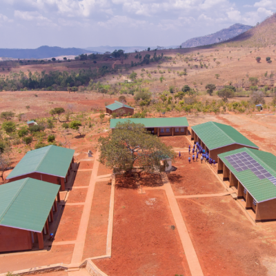 a photo from up in the air looking down on buildings with solar panels on the roof in the African desert in Mbongozi