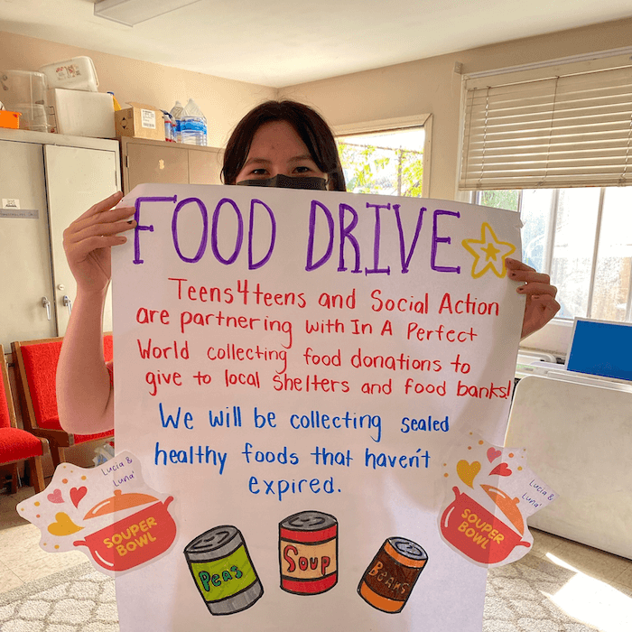 a girl holds up a home made sign for her food drive asking for food donations