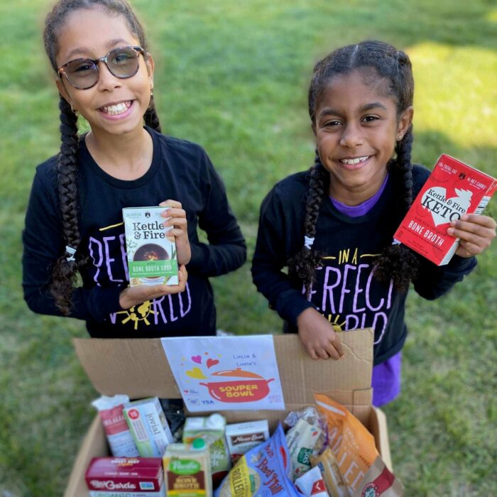 Lucia and Luna hold up food they collected for their food drive