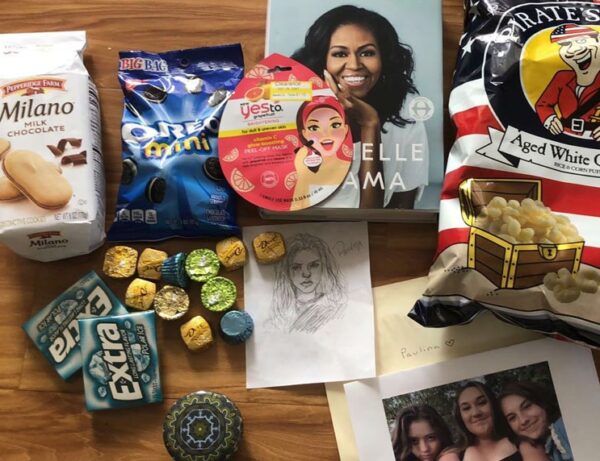 photo of care package contents on a table including Mint Milanos, Oreos, a bag of Pirates Booty, some drawings and Michelle Obama's book